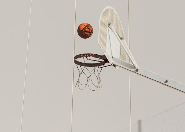 Free photo basketball falling in hoop against wall