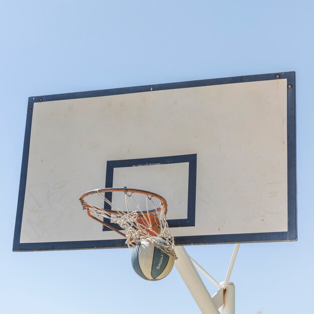 澄んだ空に対してフープを通り抜けるバスケットボール