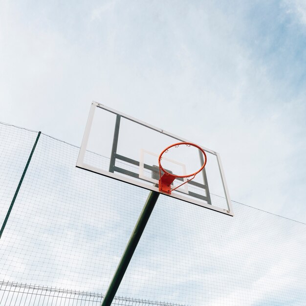 Basketball hoop and net on fence with sky view 