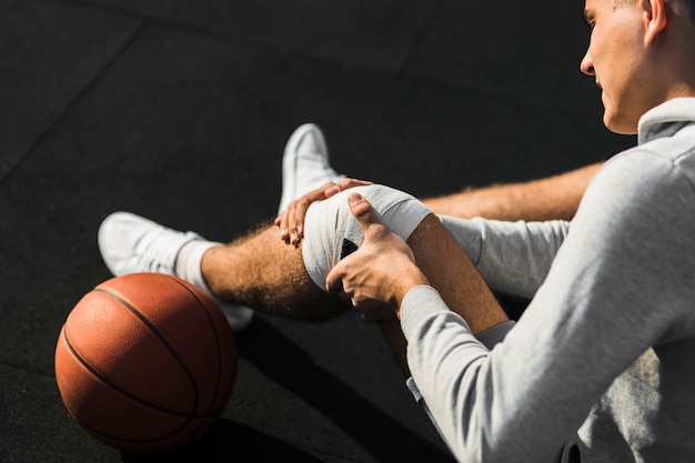 Free photo basketball player applying bandage on knee