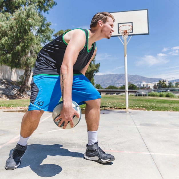 A basketball player holding ball at outdoors court