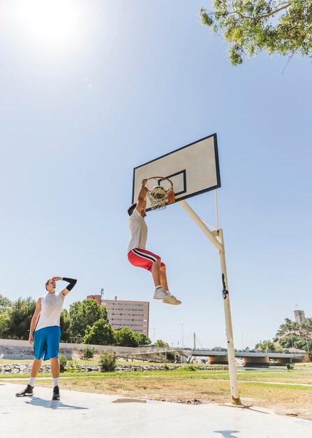 Basketball player performing slum dunk on a street court