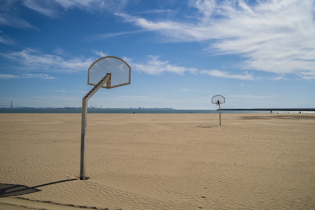 Basketball rings at the beach with a cloudy blue sky