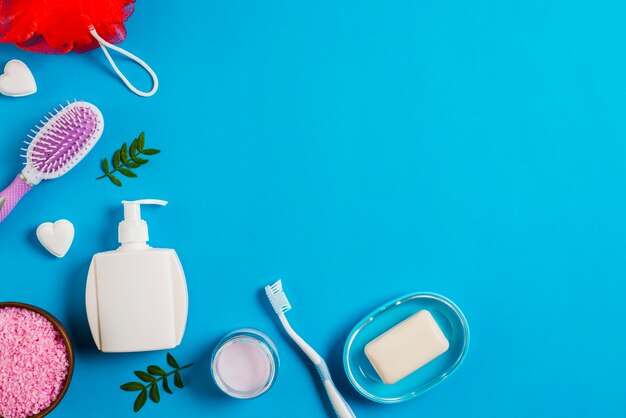 Bath products with salt; toothbrush; sponge and hairbrush on blue background