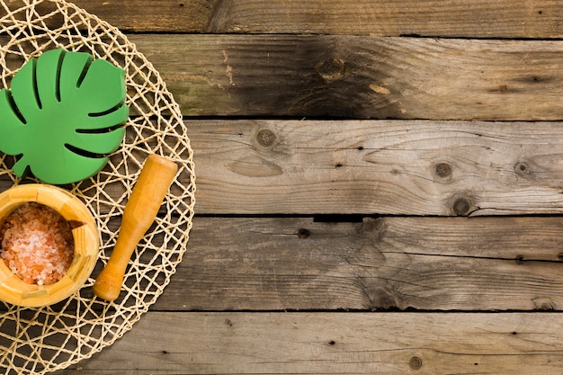 Free photo bath salt in mortar with pestle and wooden leaf on table