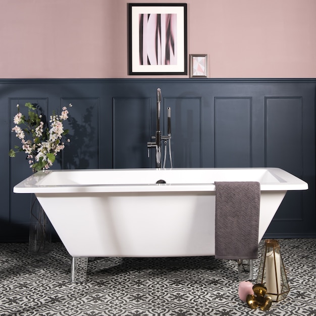 진한 파란색과 파스텔 핑크색 벽과 무늬가 있는 세라믹 타일 바닥이 있는 욕실의 욕조