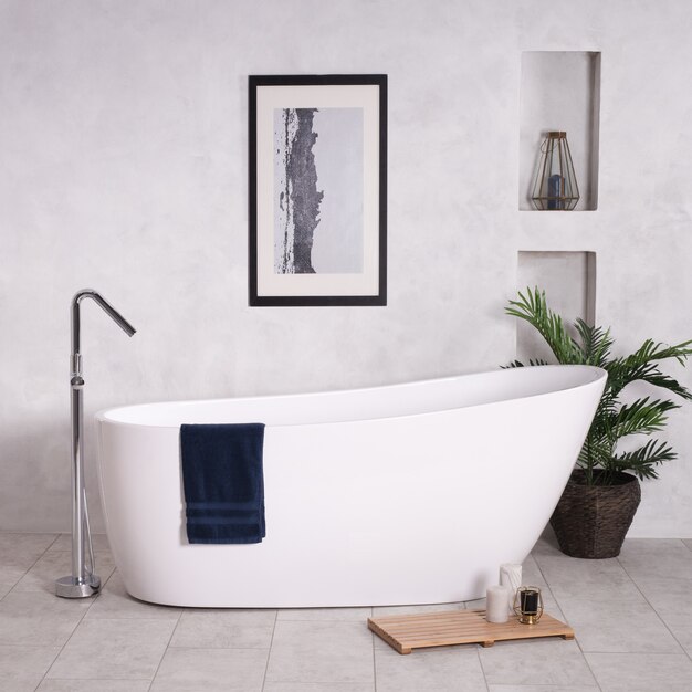 Bathtub in a bathroom with a houseplant and candles next to it