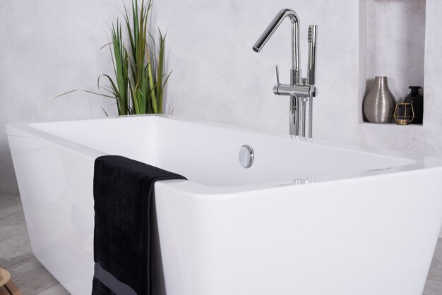 Bathtub in a bathroom with a towel on it and a houseplant in the corner