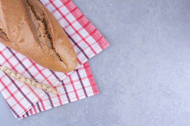 Baton bread on a towel on marble surface