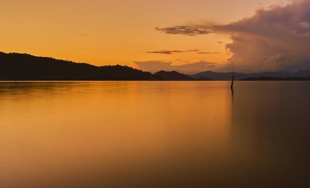 無料写真 湾の風景 日没時に太陽に照らされた海と山の景色を望む、長時間露光とぼやけた背景 スクリーンセーバーまたは壁紙のアイデア