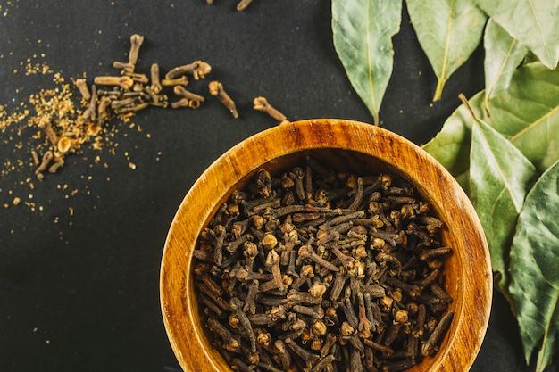 Bay leaves near bowl with cloves