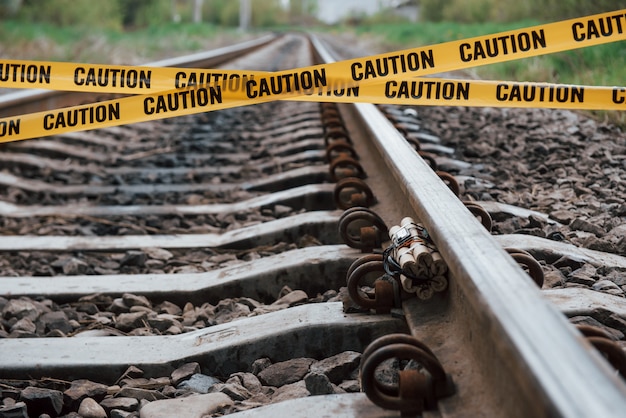 Sii consapevole. esplosivo pericoloso che giace sulla ferrovia. nastro giallo di avvertenza davanti