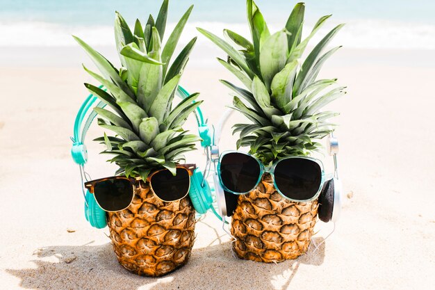 Beach background with pineapples wearing headphones and sunglasses