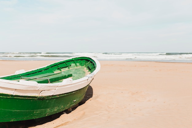 Beach concept with green boat