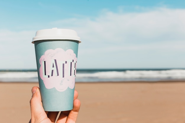 Foto gratuita concetto della spiaggia con la tazza di carta della tenuta della mano