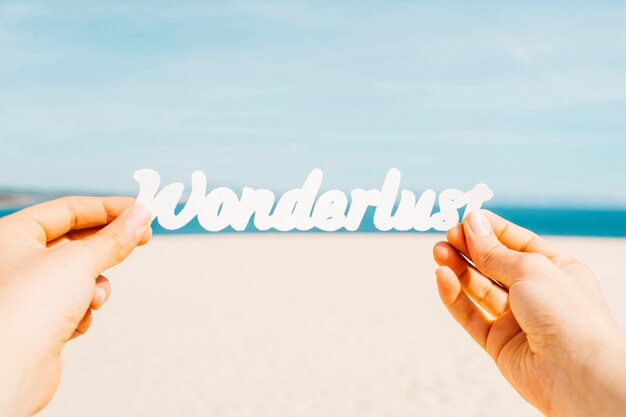 Beach concept with hands holding wonderlust letters