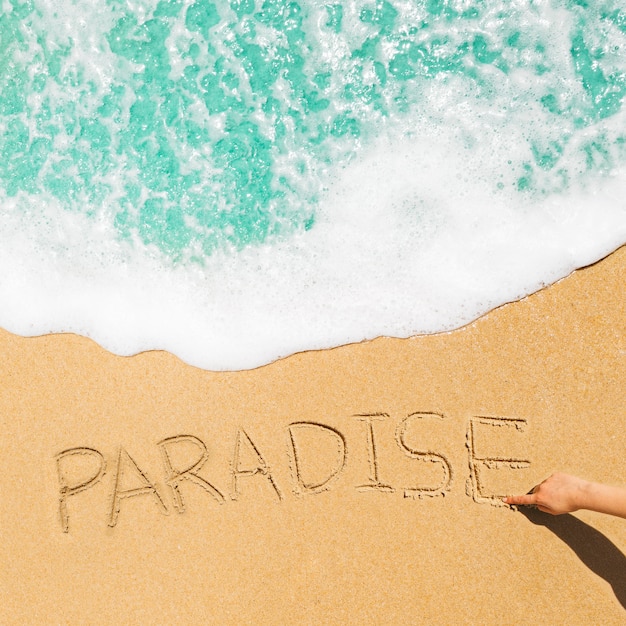 Free photo beach concept with paradise written in sand