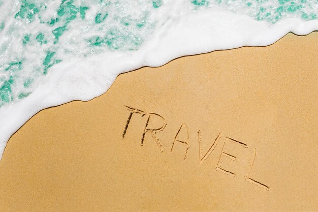 Beach concept with travel written in sand