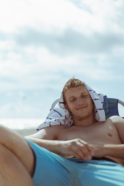미국 플로리다주 마이애미 비치, 해변에서 일광욕용 라운저를 입고 휴식을 취하는 젊은 남자.