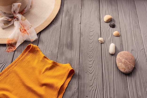 ビーチウェアオレンジ​女性​トップ​衣装​帽子​バッグ​日焼け​止め​サングラス​小石​。​夏​の​背景