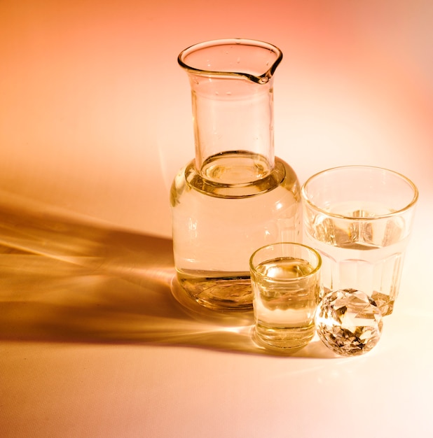 Beaker and two water glasses with shadow on colored background