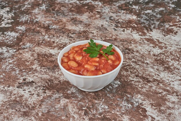 Beans soup in tomato sauce in a ceramic cup.