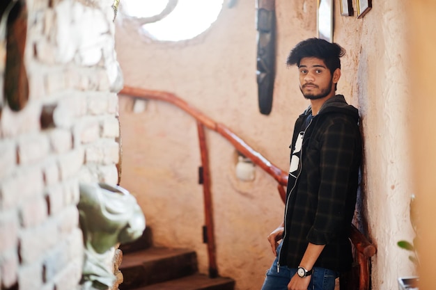 Beard asian man in casual wear stand inside house on stairs against window