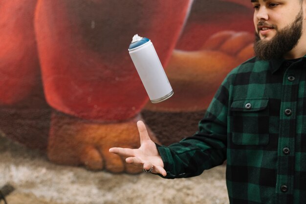 Beard young man throwing spray bottle in air