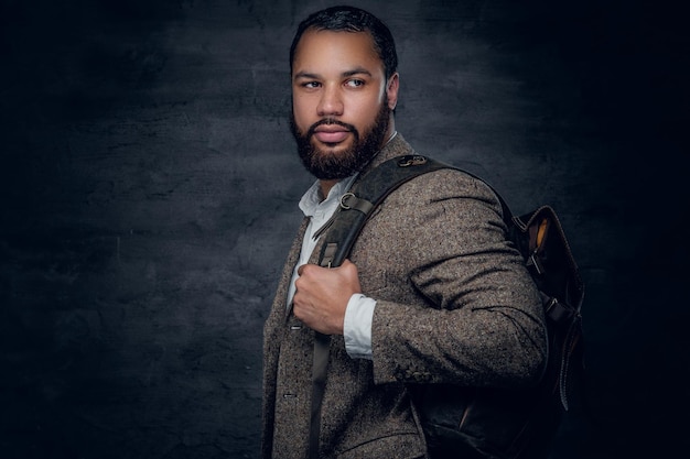 Free photo bearded black man in a suit holds backpack.