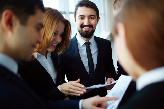 Bearded businessman surrounded workmates