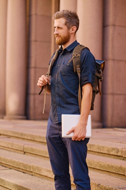 Free photo the bearded casual traveler male sits on a step and using a tablet pc.