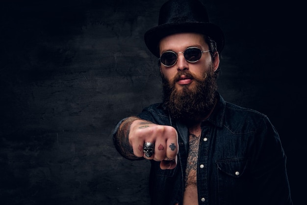 Free photo bearded cheeky man is showing fist while posing for photographer.