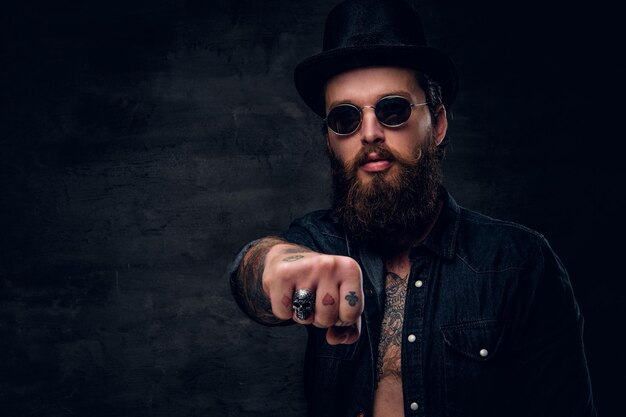 Bearded cheeky man is showing fist while posing for photographer.