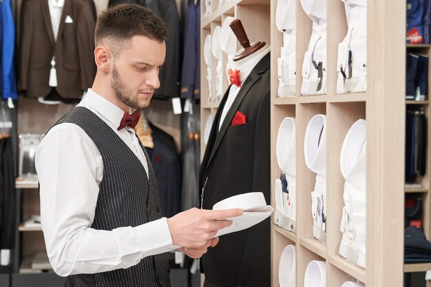 Bearded confident man choosing shirt in shop.