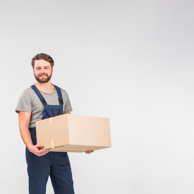 Bearded delivery man standing with big box