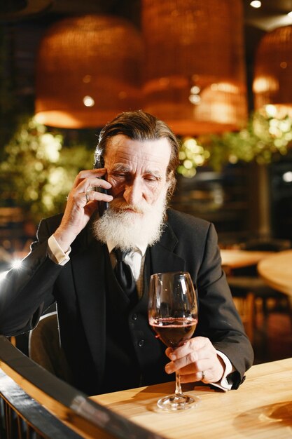 Bearded elderly businessman. Man in a restaurant. Senior in black suit.