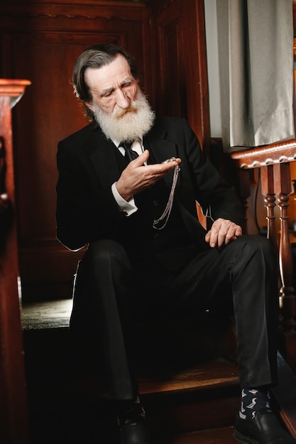 Foto gratuita barbuto anziano uomo d'affari. uomo con vecchio orologio. senior in abito nero.