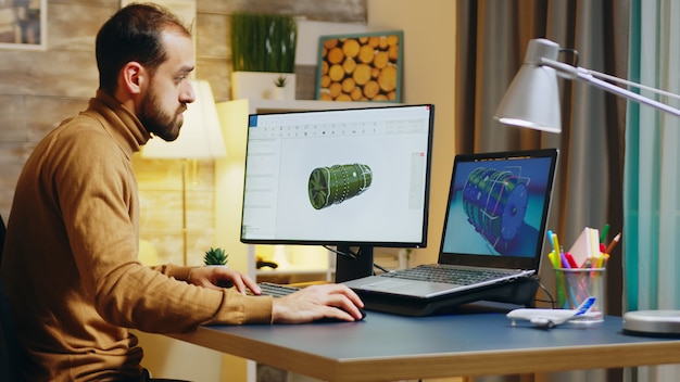 Bearded engineer sitting at his desk in home office working on a turbine.