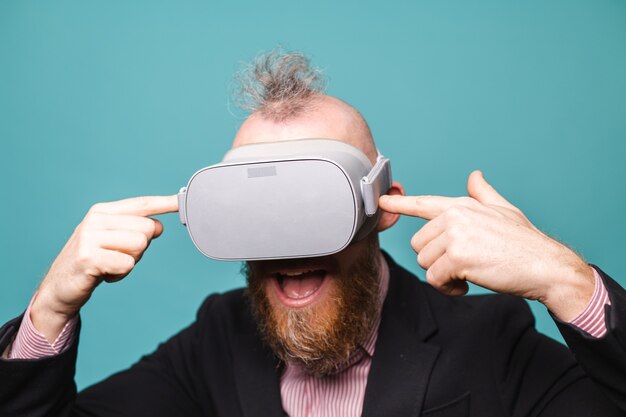 Bearded european businessman in dark suit isolated, wearing vr glasses on head with excited amazed shocked face open mouth