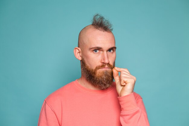 Bearded european man in casual peach isolated, mouth and lips shut as zip with fingers