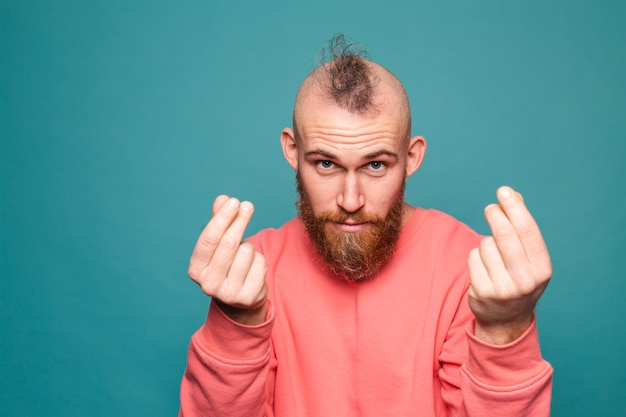 Bearded european man in casual peach isolated, rubbing fingers doing money gesture