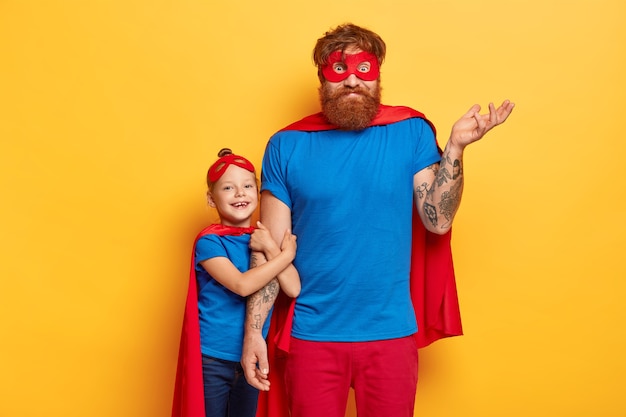 Bearded ginger father looks confusingly, raises tattooed arm