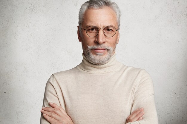 Bearded grey-haired elderly man wearing turtleneck