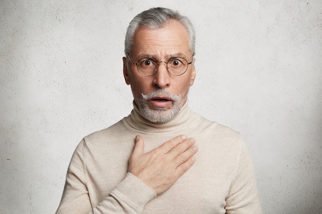 Bearded grey-haired elderly man wearing turtleneck