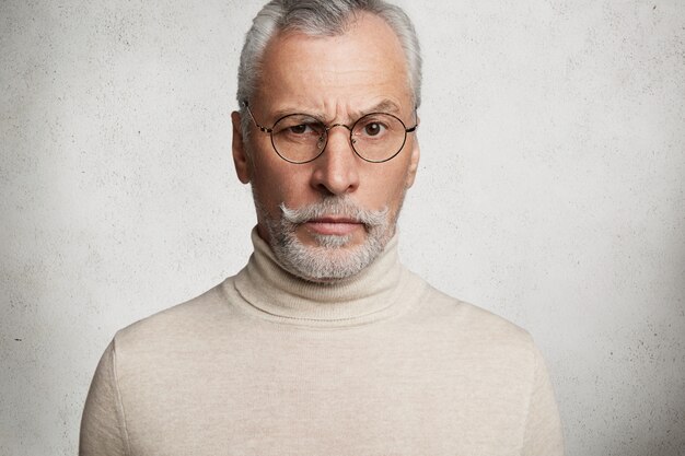 Bearded grey-haired elderly man wearing turtleneck