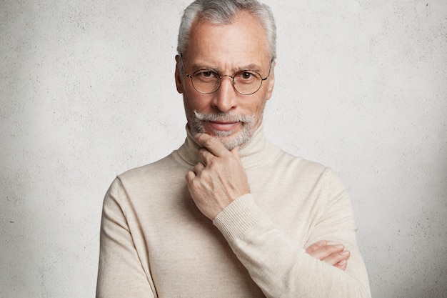 Bearded grey-haired elderly man wearing turtleneck