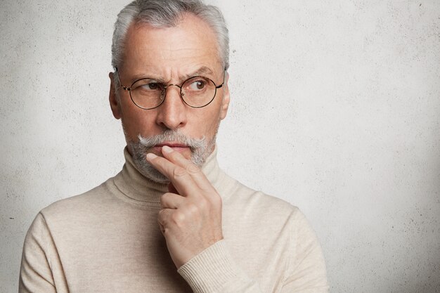 Bearded grey-haired elderly man wearing turtleneck