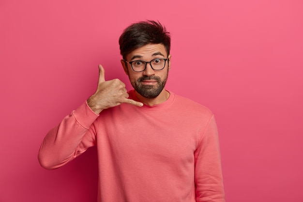 Free photo bearded handsome young man makes phone gesture