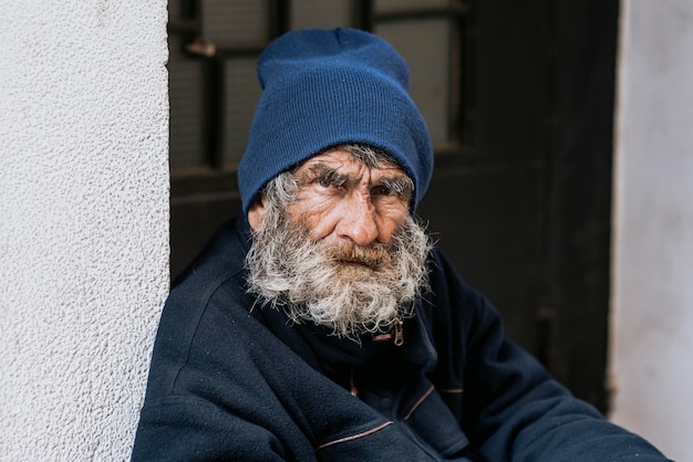 Free photo bearded homeless man on doorstep