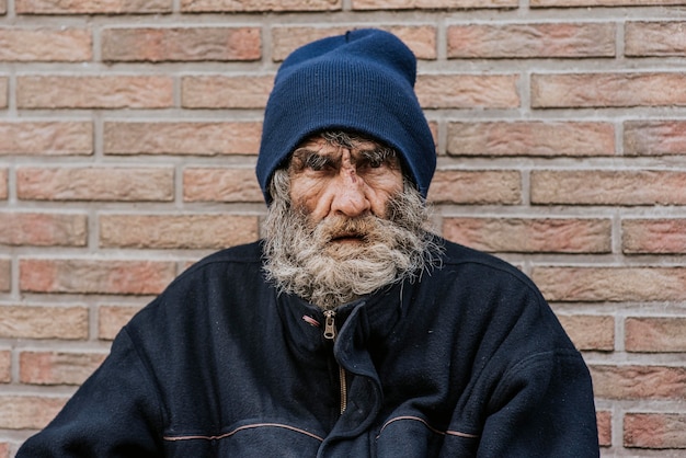 Bearded homeless man in front of wall